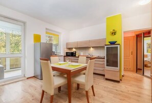 A combined dining area and kitchenette with a table for four, bright walls, and a view of the outdoors.