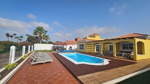 Spacious patio with heated pool, sun loungers, dining area, garden hut, BBQ