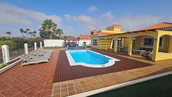Spacious patio with heated pool, sun loungers, dining area, garden hut, BBQ