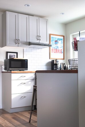 Kitchen has many amenities - dishes, cutlery, pots, small appliances .