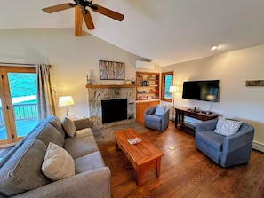 The living room is outfitted with a wood burning fireplace, TV and AC adjacent to a convenient breakfast bar and dining table