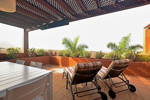 Grande terrasse avec table à manger et les chaises longues