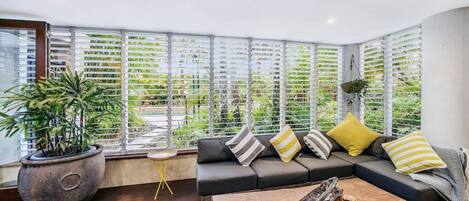 View from the kitchen out across part of the living area, through the privacy louvers, and out into the tropical gardens and pool.