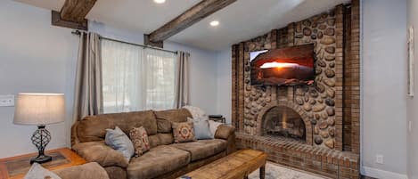 Living Room: "Cozy space with fireplace, sofa set, and a view outside."