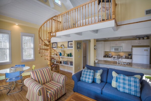 Two Sofas, Spiral Stairwell, Dining Table, Chairs, Wall Bookcase, and the Kitchen.