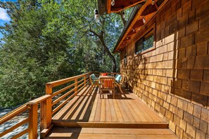 Home's deck features outdoor seating with pine tree views. - Home's deck features outdoor seating with pine tree views.