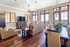 Dining Table, Chairs, Windows, and Sofas, TV, Window Doors to the Balcony.