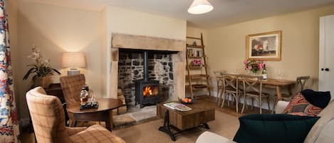 Aydon Castle Cottage - sitting room with large fireplace and dining space for four guests