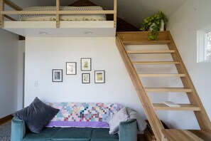 Super comfy sofa, handmade quilt, and stairs leading to the lofted bed