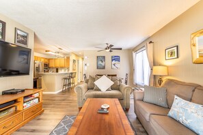 Living area with mounted flat screen TV, gas fireplace, ample seating, hardwood flooring and access to the private balcony.