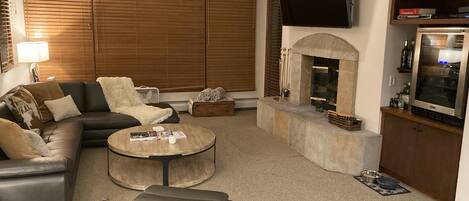 Living room with large HDTV and wood burning fireplace with plenty seating