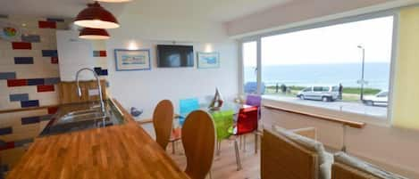 First floor: Open plan living area with a breakfast bar seating four guests. Separate dining area and sitting area looking out across the beach