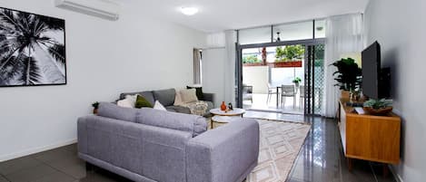 Living room with Smart TV opening onto large patio with direct access to pool area