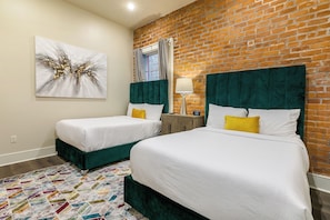 Spacious guest bedroom with two full-size beds and a designer built-in closet. Equipped with nightstands, lamps, hangers, luggage rack, alarm clock, white noise machine, and a 55'' Samsung Smart 4K TV with streaming and DIRECTV Entertainment.