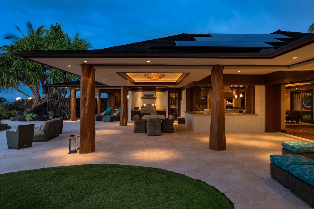 Luxury open villa with wooden beams and lit terrace at night 