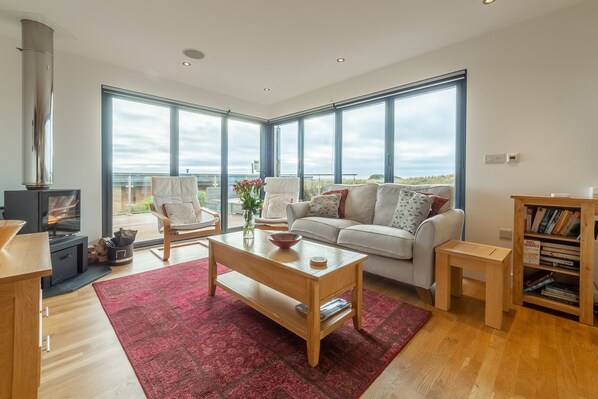 Sea Gem, St Agnes. Sitting area with a television and state-of-the-art wood burning stove. Bi-folding doors to deck
