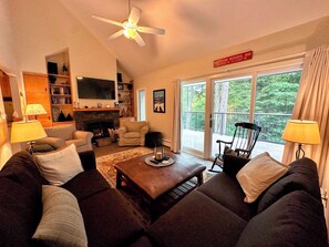 Main level living room with TV, gas fireplace, and walkout to deck