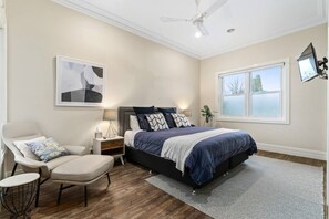 Master bedroom with king size bed, wall mounted TV and automatic blinds