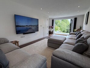 Living room with large comfy sofas, 75" TV with Freeview & Netflix
