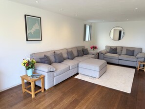 Living room with large comfy sofas, 75" TV with Freeview & Netflix.