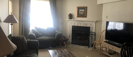 Open plan living room connects with kitchen area, with fire and flat-screen TV