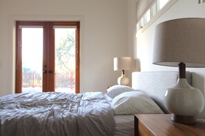 Queen-sized bed and side tables, with linens, closet, mirror and dresser.