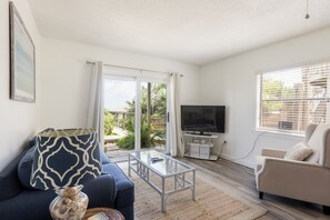 Living room with sofas, smart TV and sliders to the ocean view patio.