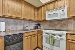 Kitchen with coffee maker, toaster, dishes, cups, glasses, cooking pots & pans.