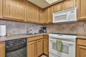 Kitchen with coffee maker, toaster, dishes, cups, glasses, cooking pots & pans.