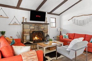 The living space includes ample seating options, a gas fireplace, and a flat-screen Smart TV for streaming.