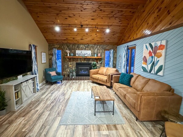 Living room with new couches and cozy fireplace for gathering. Open to dining room for good entertaining flow.