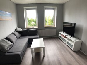 Wohnzimmer mit Schlafcouch und 55 Zoll Smart TV