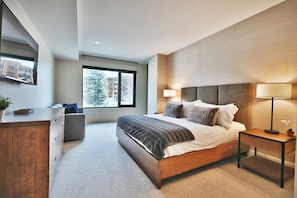 Main bedroom with luxurious king bed, upholstered headboard and wooden frame and  sofa sleeper beneath the large picture window