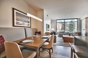 Cozy dining nook with solid wood table, upholstered high back dining chairs and upholstered bench with linear pendant beam chandelier