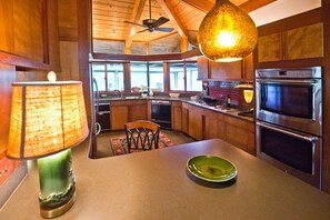 Kitchen bar looking upon counters, ovens, dishwasher and covered porch