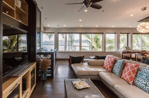 Living room has recessed lighting, ceiling fans and wall to wall windows to take in the views of Kaneohe Bay.