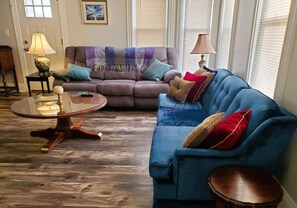 The living room with two comfortable sofas, (one reclaimed) and an armchair.