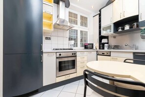 A modern kitchen with bright lighting, light-colored cabinets, and a small dining area, providing a cozy yet functional cooking space for daily living.