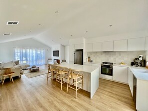 Large open-plan living/dining area with servery out to deck overlooking the pool