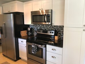 Fully-stocked kitchen with cookware, dinnerware, coffee maker, blender, and more