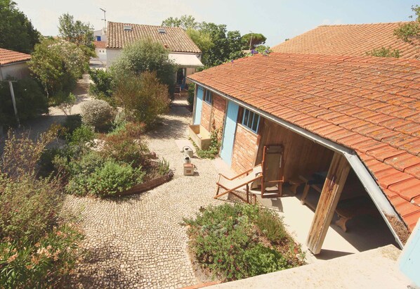 La maison et le préau de l'appartement donnent sur la cour pavée.