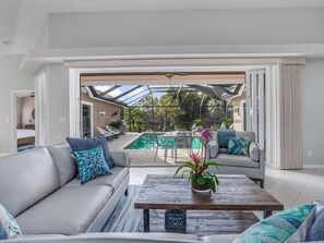 Open the door to paradise—panoramic pool and lake views from the living room