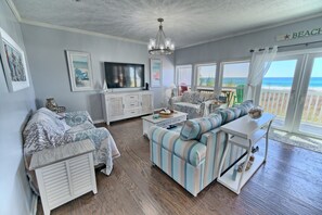 Unwind in this cozy yet stylish living room, where coastal décor and a large TV pair perfectly with sweeping ocean views.