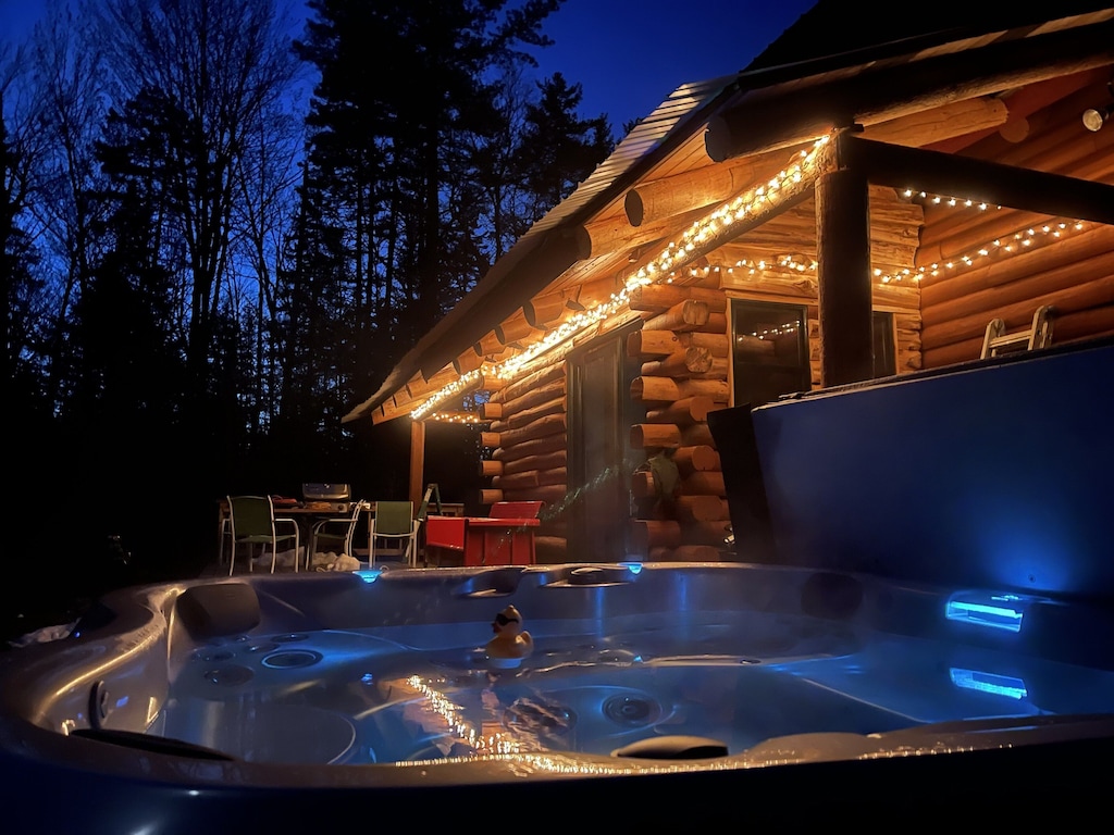 A Vermont cabin with hot tub has exterior lights that make it very romantic.