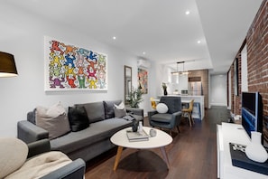 Living Room: Features a queen-size sofa bed with Art Deco design, two armchairs, and a Smart HD TV with access to Netflix, YouTube, and Prime.