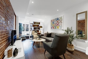 Living Room: Features a queen-size sofa bed with Art Deco design, two armchairs, and a Smart HD TV with access to Netflix, YouTube, and Prime.