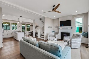 Spacious living room with fireplace, ceiling fans, and all glass sliders to deck