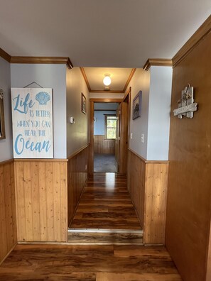Hallway leads to the full bath with stand-up shower and primary bedroom with queen size bed.