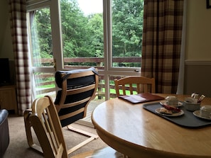 Living space with balcony overlooking the forest | Thistle Lodge - Flowerburn Holidays, Rosemarkie, near Fortrose