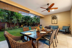 Outdoor dining on tables and chairs of the back lanai with open access inside the home.